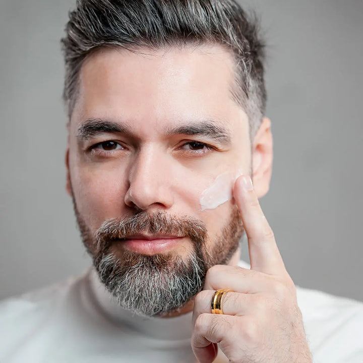 Homem passando hidratante facial Major com proteção solar na pele.