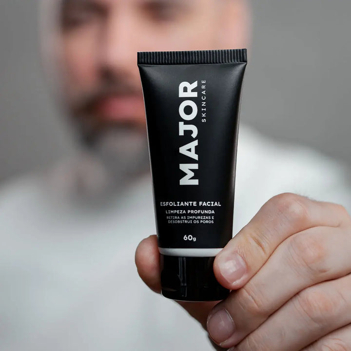 Homem segurando esfoliante facial Major para limpeza profunda da pele masculina.