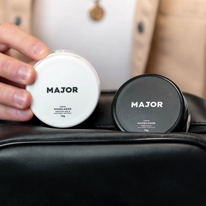 Pomadas modeladoras Major efeito seco e úmido em embalagens preta e branca, exibidas em necessaire, para penteados masculinos profissionais.
