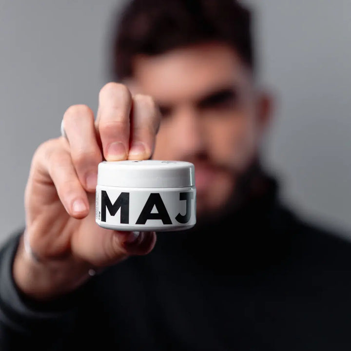 Homem segurando pote da pomada efeito matte Major em destaque, produto profissional para estilo e fixação média.